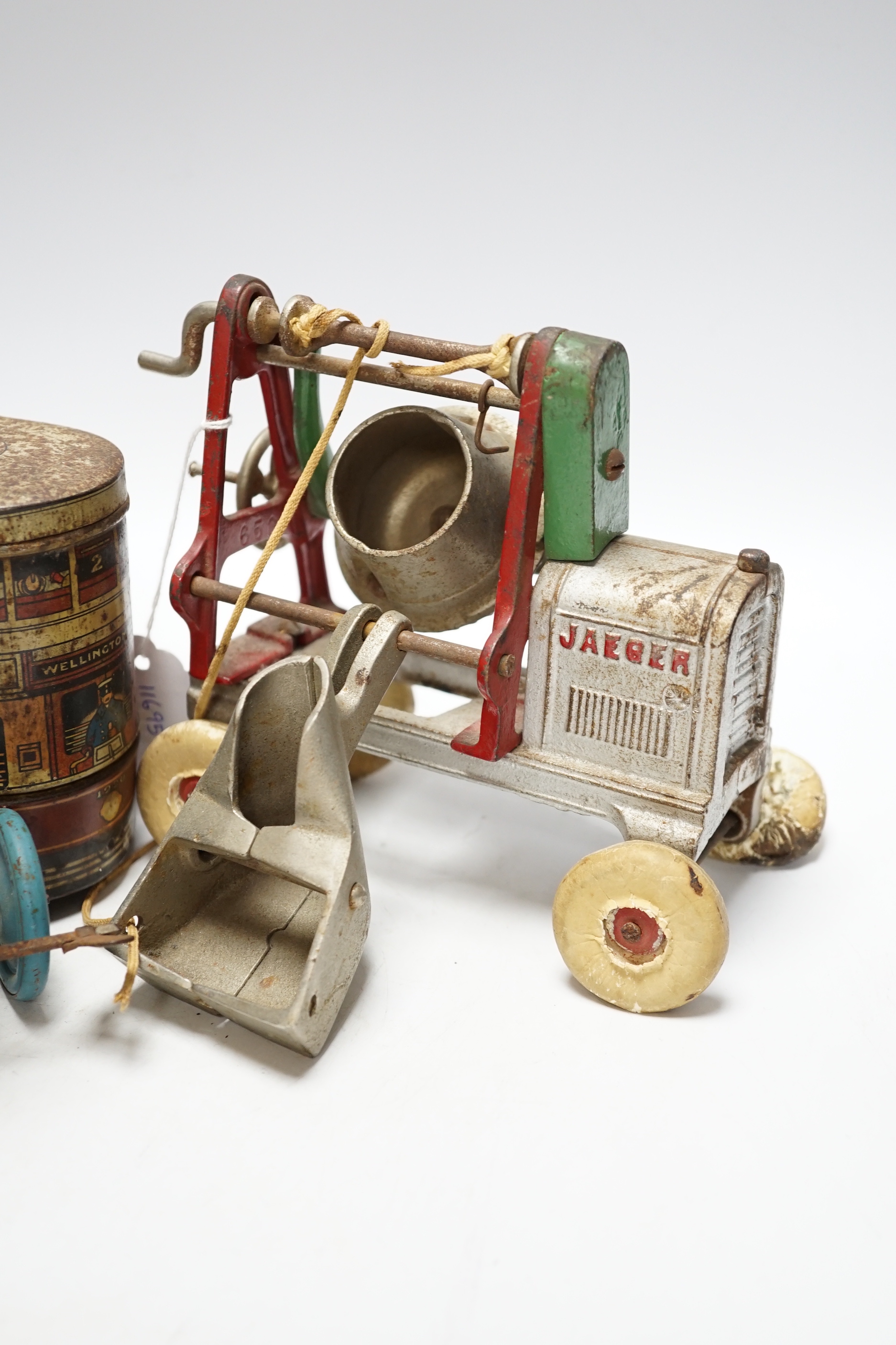 Three tinplate/cast iron toys; a Jaeger cast iron concrete mixer, a Carr’s tinplate biscuit tin in the form of a tram, and a clockwork teddy bear on a tricycle, tram 22cm long